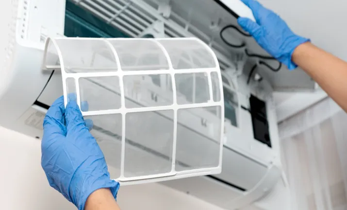 Teknisi membersihkan filter unit AC indoor