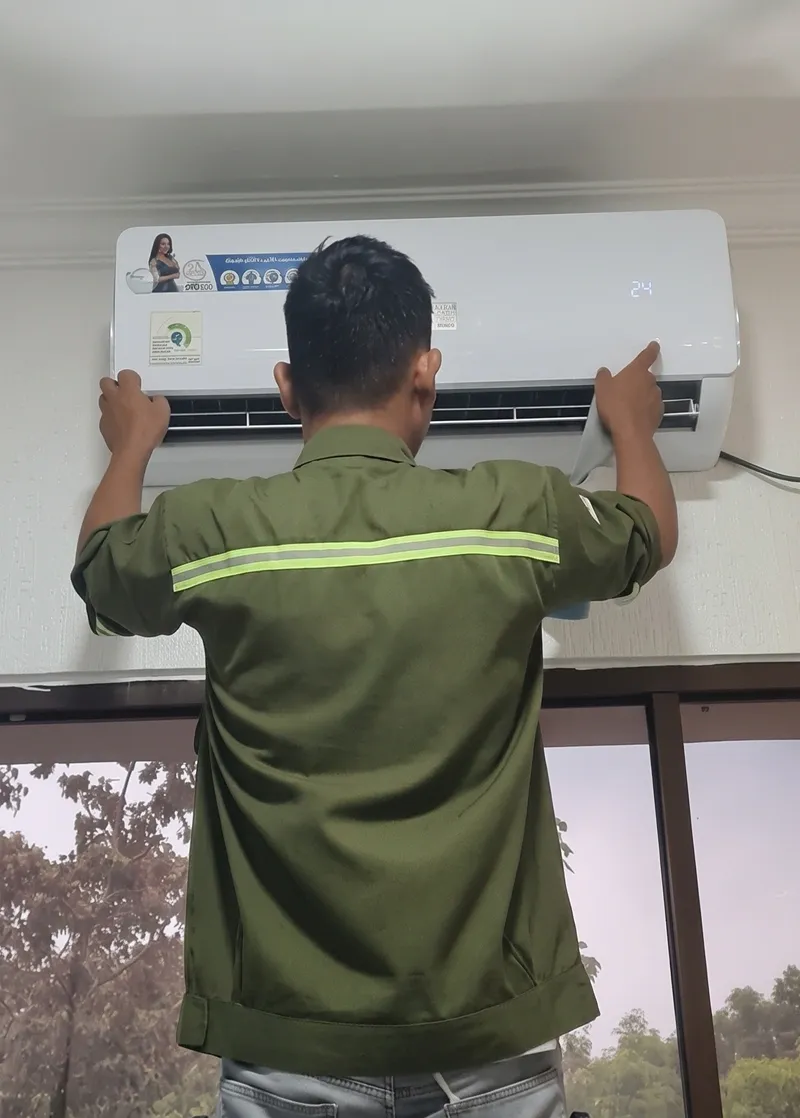Teknisi mengecek unit AC indoor dan pengaturan suhu